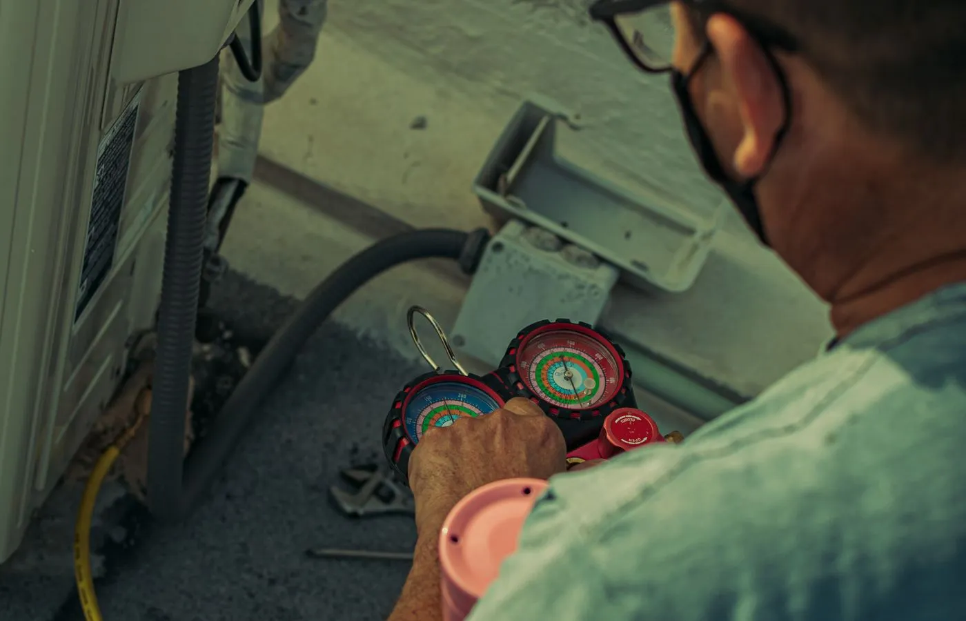 HVAC technician checking refrigerant pressures on an outdoor air conditioning unit